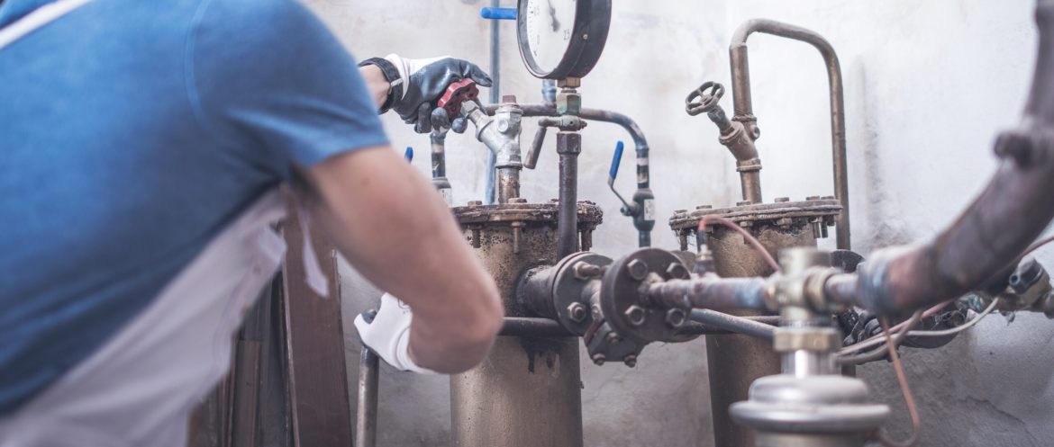 Plumbing Worker Job. Caucasian Plumber Checking on Water Heating Plumbing System.